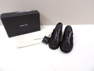 des mocassins en cuir noir, avec une boîte posée sur une table à côté