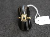 une image représentant une bague noire et dorée ornée d'une pierre bleue