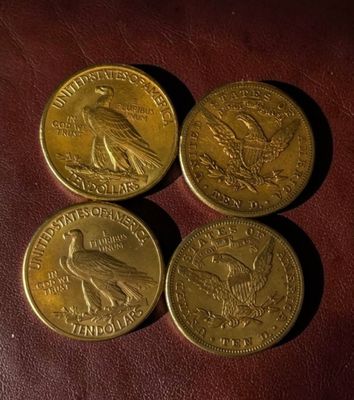 three gold coins sitting on top of a brown leather surface