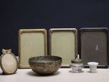 trois cadres et un bol posés sur une table à côté d'une bougie