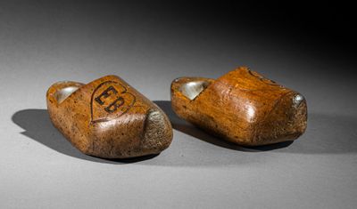 pair of carved wooden shoes with initials on them sitting on a table