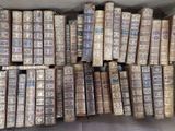 une boîte pleine de vieux livres posée sur le sol