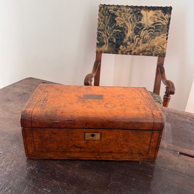 an old wooden box sitting on a table with a chair in the background