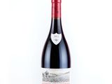 the bottle of red wine is sitting on a white surface
