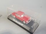 a red car in a clear box next to a pair of scissors