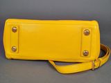 a close up of a yellow purse on a gray surface