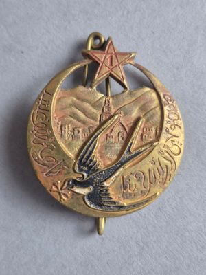 une petite médaille en or sur laquelle figurent un oiseau et une étoile