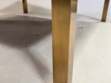 a close up of a brass coffee table with a glass top