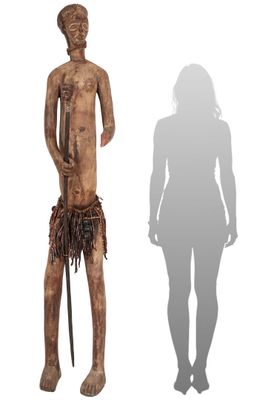 wooden statue of a man holding a cane and standing next to a shadow of a woman