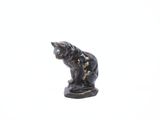 une petite statue représentant un chat posée sur une surface blanche