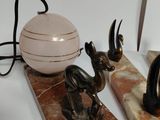 two statues of animals and a ball on a marble stand