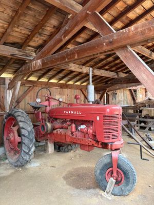 un tracteur rouge garé à l'intérieur d'une grange au toit en bois
