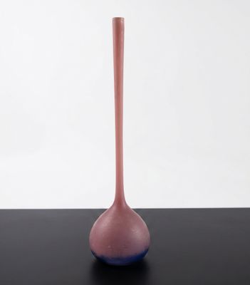 pink glass vase on a black table against a white background