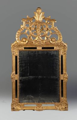 an ornately carved mirror with a gold frame on a grey background