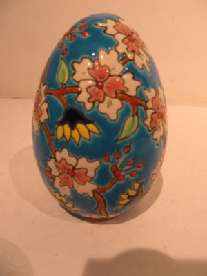 a blue egg with flowers on it sitting on a table
