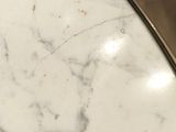 a close up of a white marble table top on a wooden floor