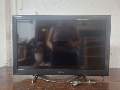 une télévision posée sur une table, avec une personne à l'arrière-plan