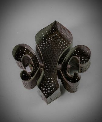 un objet métallique percé de trous, posé sur une surface blanche