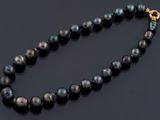 un gros plan d'un collier de perles noires posé sur une surface noire