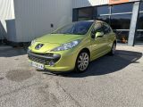La voiture verte est garée devant un immeuble, sur un parking.