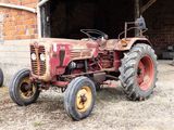 un tracteur rouge garé devant un immeuble