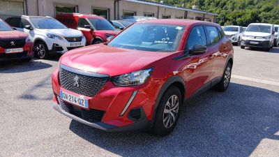 La voiture rouge est garée sur le parking, à côté de nombreuses autres voitures.