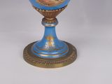 a blue and gold vase with a picture of a woman on it