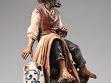 figurine of a man with a hat sitting on a rock