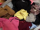 une valise pleine de vêtements et un sac à dos posés par terre