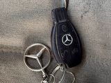 a car key and a mercedes keychain hanging from a bag
