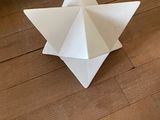 une étoile en origami blanche posée par terre à côté d'une porte