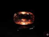 an orange sapphire stone on a black surface
