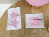 three pink hair clips sitting on a table next to a pink bowl