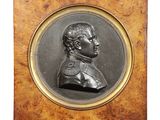 a bronze portrait of a man with a beard in a wooden frame