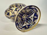 an image of a blue and gold vase sitting on a white surface