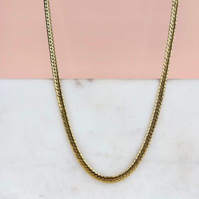 un collier à chaîne en or posé sur une surface en marbre