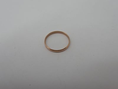 a gold wedding ring on a white surface