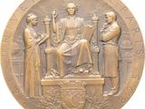 an image of a bronze medal with a statue of a woman and two men