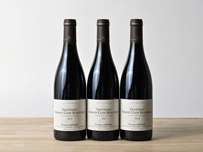three bottles of wine sitting on top of a wooden table