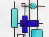 a blue and green glass wall hanging on a white wall