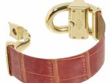an image of a bracelet with a gold clasp and a red alligator skin