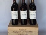 trois bouteilles de vin rouge dans une caisse en bois posée sur une table