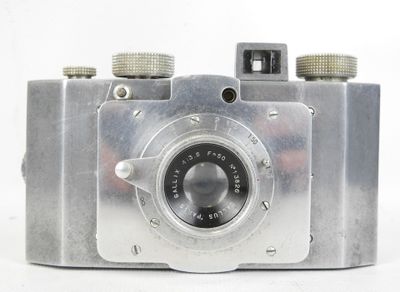 un appareil photo argenté posé sur une surface blanche