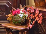 un panier de fleurs posé sur une table devant une commode