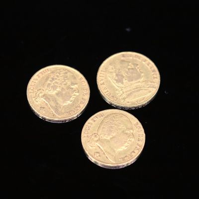 three gold coins on a black surface