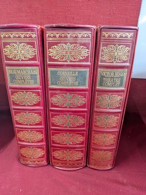 trois livres rouges sont alignés sur un tissu rouge
