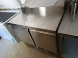 a stainless steel counter top with a trash can in the corner