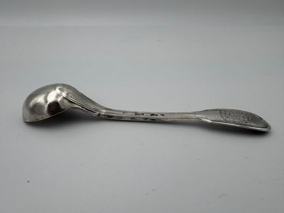 une cuillère en argent posée sur une table, sur fond blanc