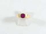 gros plan d'une bague en or avec une pierre en rubis
