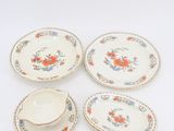 four pieces of porcelain plates with floral designs on them on a white surface